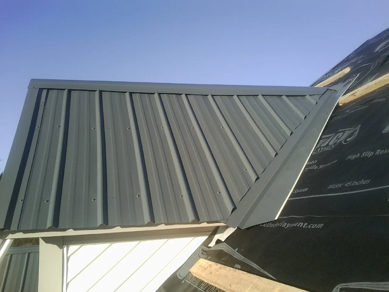 Gray metal roof panels going on over a garage gable in Guilderland Center