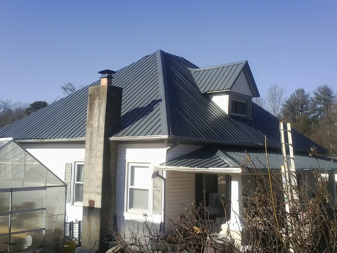 Dark blue standing seam metal roof on a white farmhouse with dormer — Slate & Tile Roof Repair by Roofing Brothers in Guilderland Center
