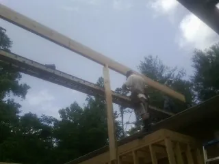 Carpenter setting a ridge beam over a new addition frame — Ice Dam Removal by Roofing Brothers in Guilderland Center