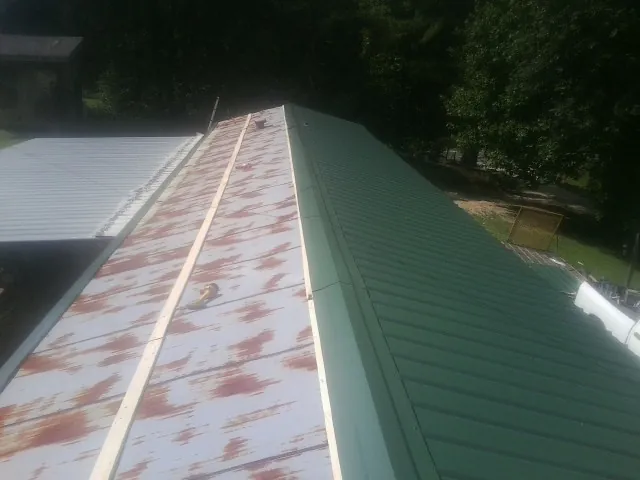 Old rusted panels beside newly installed green metal roofing — Wind Damage Roof Repair by Roofing Brothers in Guilderland Center