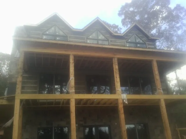Dormers and porch framing on a large log home under construction — Roof Coating work by our crew in Guilderland Center