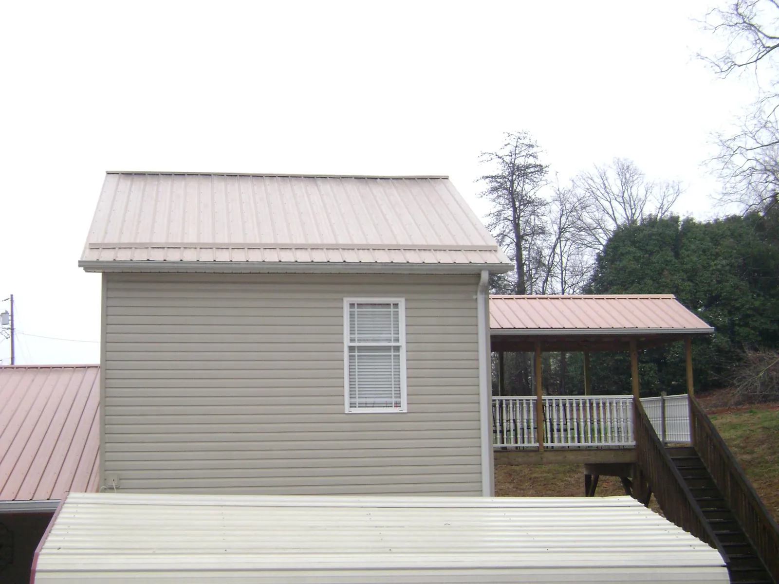 Tan metal roofs on a two story addition and attached porch, from a Roof Replacement job in Guilderland Center
