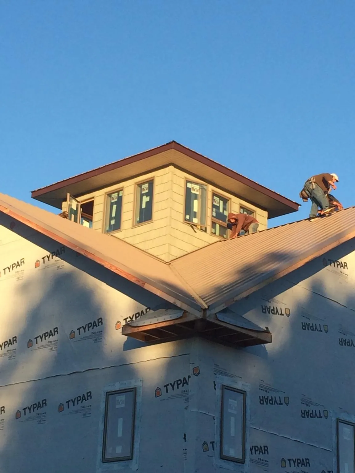 Roofers working around a rooftop cupola on a new metal roof at sunset — Roof Waterproofing in Guilderland Center by Roofing Brothers